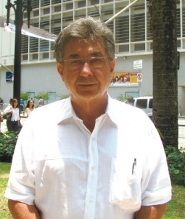 Descrição de Imagem: Fotografia do Dr. José Carlos do Carmo, conhecido como Dr. Kal. Um homem com cabelos grisalhos, veste uma camisa social branca e usa óculos.