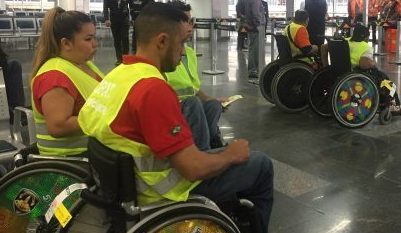 Descrição de Imagem: Trabalhadores cadeirantes uniformizados com um colete amarelo.