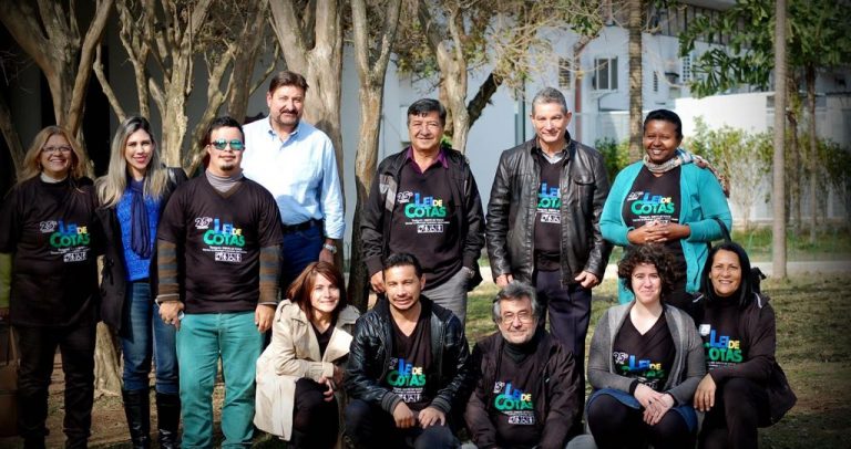 No Parque do Ibirapuera, de camiseta preta com o logotipo da Lei de Cotas em azul. dr. Kal do Carmo está cercado de parceiros da Câmara Paulista para Inclusão, como Carlos Clemente, da ONG Espaço Cidadania, Marinalva Cruz, secretária adjunta da secretaria municipal da Pessoa com Deficiência, Maria Rosimar da ONG Arestrelas, Ariadne Senna, da Câmara Paulista, entre vários outros presentes.