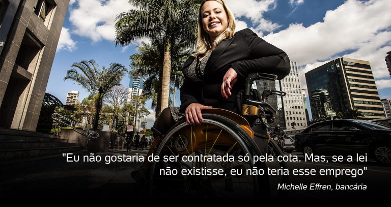Descrição da imagem: Numa cadeira de rodas, Michelle está sorrindo, à frente de um jardim com palmeiras ao fundo. Ela é loira, está de casaco marrom, apoia o cotovelo esquerdo no encosto da cadeira e a mão direita segura a roda. Ela tem o cabelo liso na altura dos ombros. Texto: Eu não gostaria de ser contratada só pela cota. Mas se a lei não existisse eu não teria esse emprego.