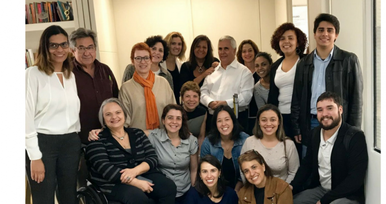 Descrição da Imagem: Foto com 18 pessoas, entre elas 4 homens, que integram a força de trabalho para o guia temático de inclusão nas empresas
