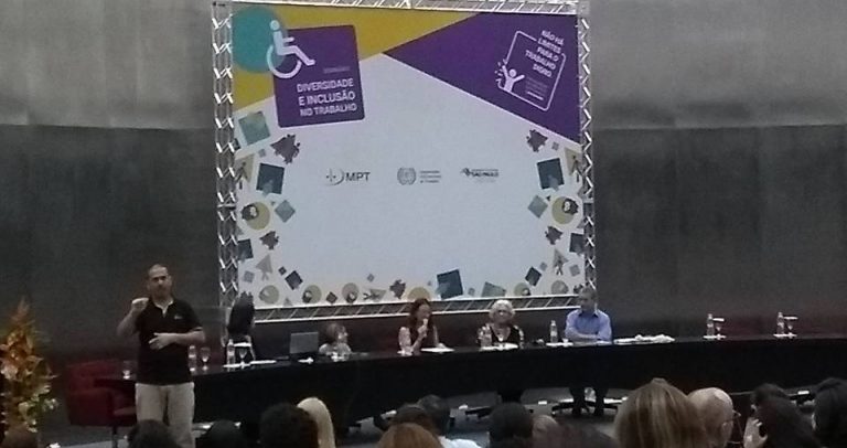 Descrição da imagem: Ao fundo, telão com as logos do Seminário. À esquerda, o intérprete de Libras. Sentados, da esquerda para a direita: Thays Toyofuku, Nalva Cruz, Sofia Vilela, Marta Gil e Carlos Aparicio Clemente, do Espaço da Cidadania.