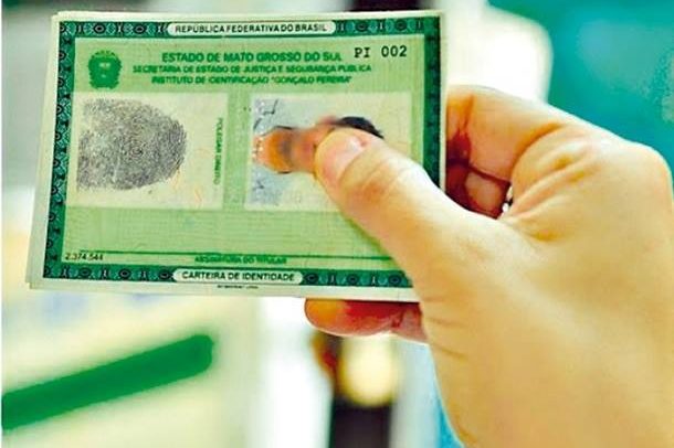 Descrição da imagem: pessoa segurando uma carteira de identidade.