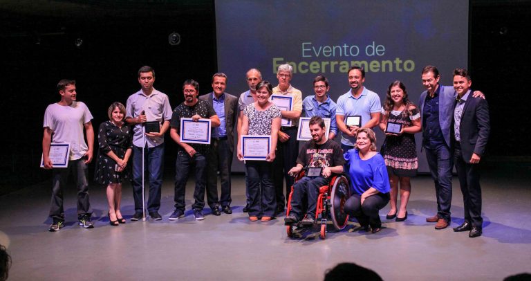 Descrição da imagem: No palco, alunos homenageados com seus certificados, estão ao lado de representantes da Dell e parceiros públicos e privados do programa.