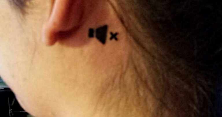 Descrição da imagem: foto em close mostra uma tatuagem feita atrás da orelha de uma mulher, onde aparecem um microfone e um X, que significam "sem áudio".