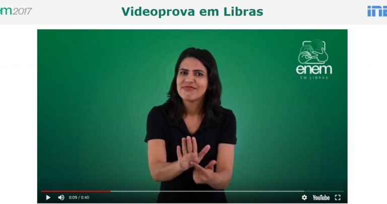 Foto de uma moça fazendo sinal em Libras, com o fundo verde, e o texto Videoprova em Libras