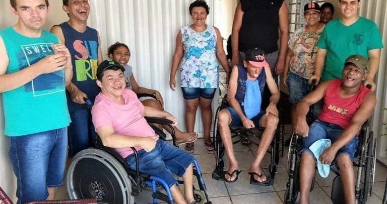 grupo de 11 pessoas com deficiência, quatro deles em cadeiras de rodas, posam para a fotografia