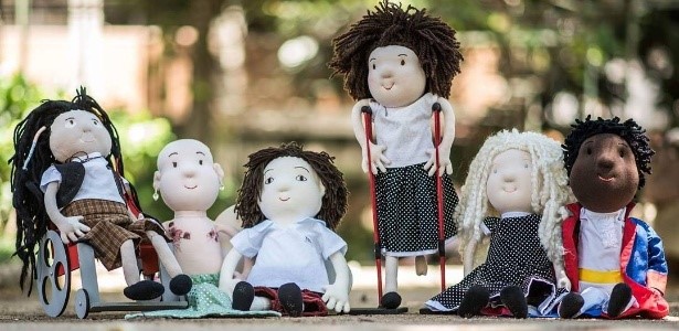fotografia mostra seis bonecos de pano. Entre eles uma cadeirante e uma com a perna direita amputada
