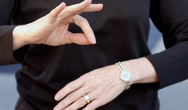 Detalhe das mãos de mulher utilizando a Libras (Língua Brasileira de Sinais)