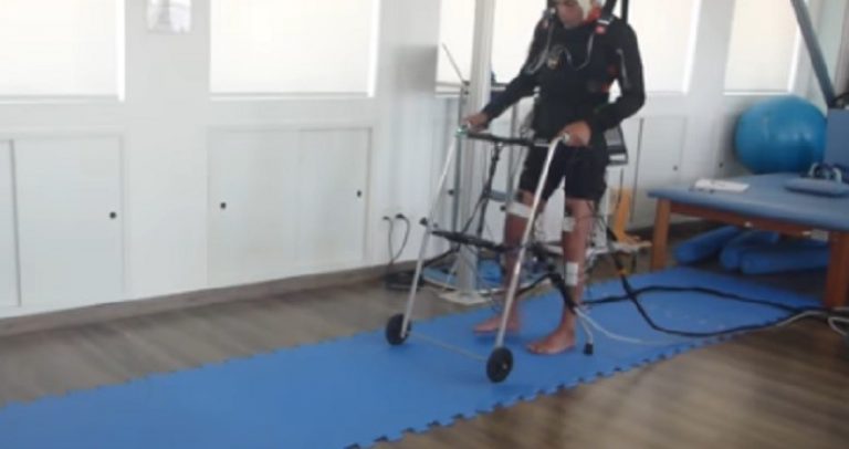 paciente exercita o caminhar utilizando a técnica desenvolvida pelo cientista brasileiro, Miguel Nicolelis: um suporte corpóreo e um andador.