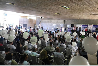 foto de público com aproximadamente 200 pessoas, segurando balões brancos e assistindo a programação