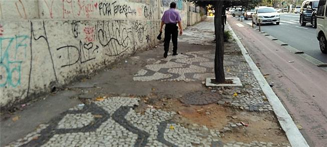 foto de calçada de mosaico português. Faltam muitas pedras, o que forma buracos no calçamento.
