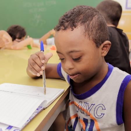 Foto de um menino que escreve em um caderno