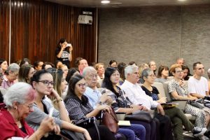 Foto da plateia no auditório da Superintendência Regional do Trabalho. O auditório está lotado, com cerca de 100 pessoas sentadas.