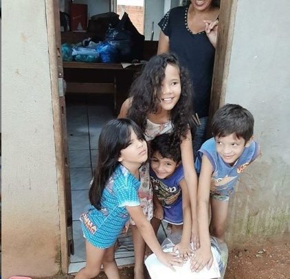 Famílias recebem cestas com doações e mostram o documento da ASID