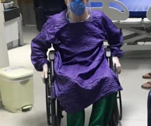 Foto do médico Heider Irinaldo. Ele está sentado em uma cadeira de rodas. Usa máscara, roupa de proteção e luvas.