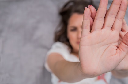 Mulher branca com o braço esticado e a mão aberta, em sinal de defesa