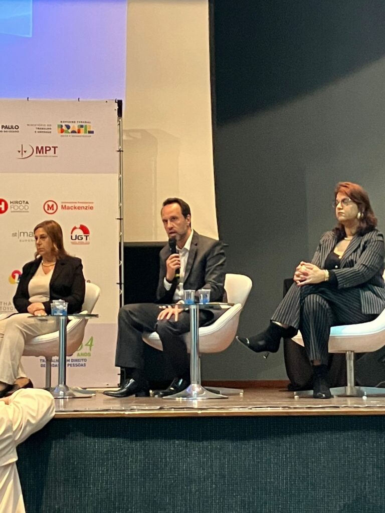 Foto do palco, onde estão sentados lado a lado Silvia Grecco, Armando Jr e Michele Reis Moreira.