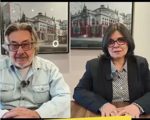 foto de José Carlos do Carmo, Kal, e de Maria de Fátima Silva. Kal tem a pele branca. O cabelo, barba e bigode curtos grisalhos, usa óculos de grau e uma camisa azul claro. Maria de Fátima tem a pele branca, cabelo preto liso na altura do ombro, usa óculos de grau, paletó preto sobre uma camisa cinza. 