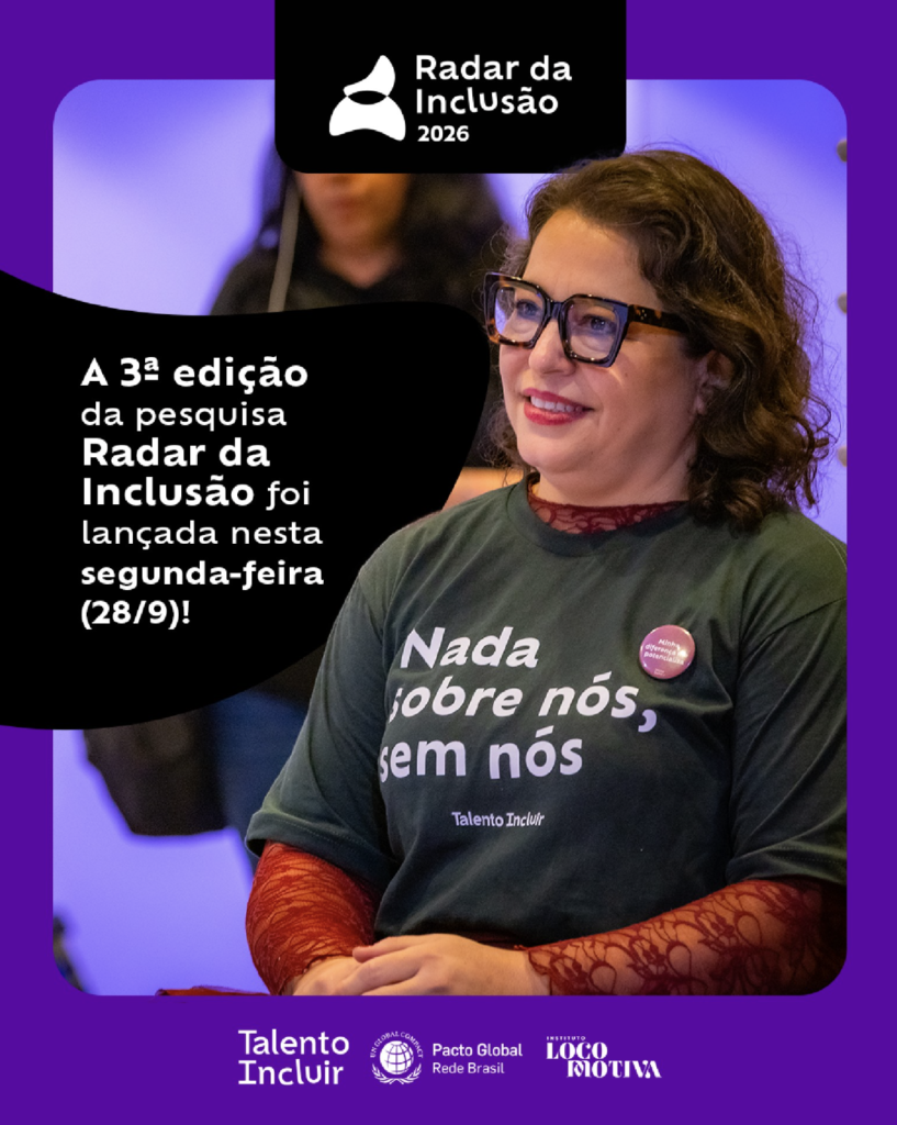 Foto de Carolina Ignarra. Ela é uma mulher branca de cabelo e olhos castanho escuros, usa um óculo de grau com armação grande marrom escuro. Esté vestindo uma camiseta preta com a frase "Nada sobre nós, sem nós" e, por baixo, uma blusa de renda vermelha de mangas compridas.