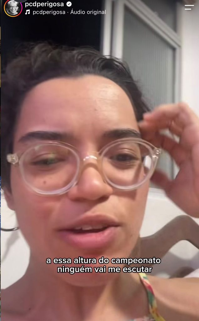 Amanda Soares é uma mulher de pele clara, cabelo curto castanho, olhos castanhos, usa óculos de grau.