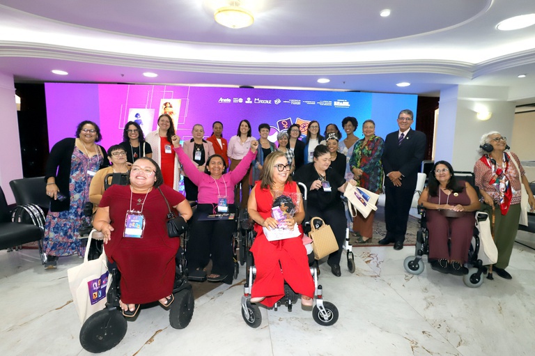 grupo de aproximadamente 20 mulheres com deficiência comemorando a criação do fórum